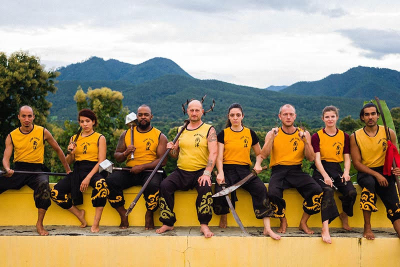 Instructors sitting on wall with Shaolin Kung Fu weapons.