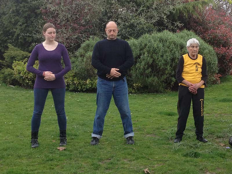 Lucinda Master Iain and Sheila practicing Qigong in a line outside
