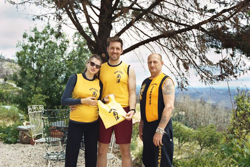 Elodie, Dan, and Master Iain holding a tiny Nam Yang Uniform