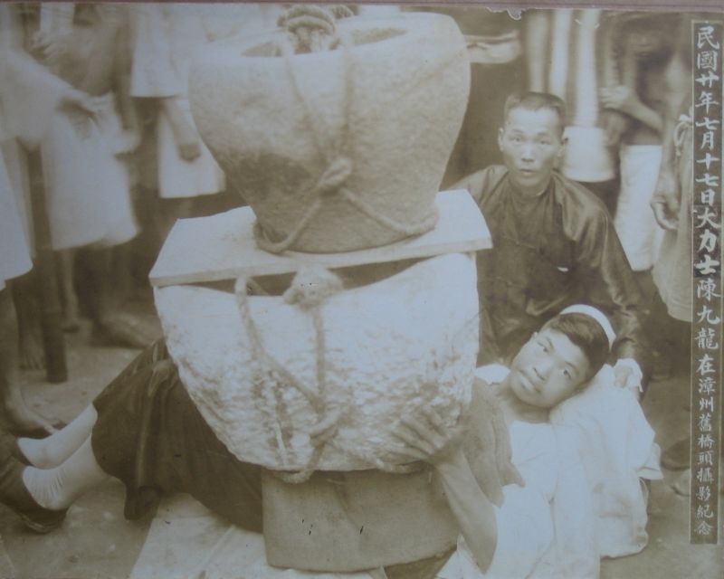 Master Tan with a large boulder on him performing iron shirt qigong